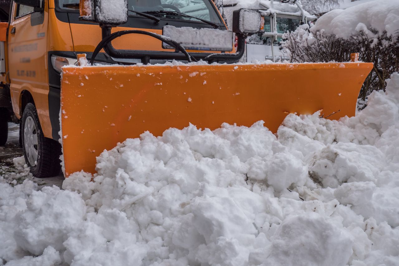 Hausmeister räumt die Straße mit dem Schneeräumer